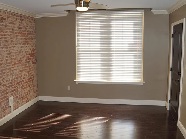 Living room with accent brick wall, the door to the right is the entrance to the apartment.