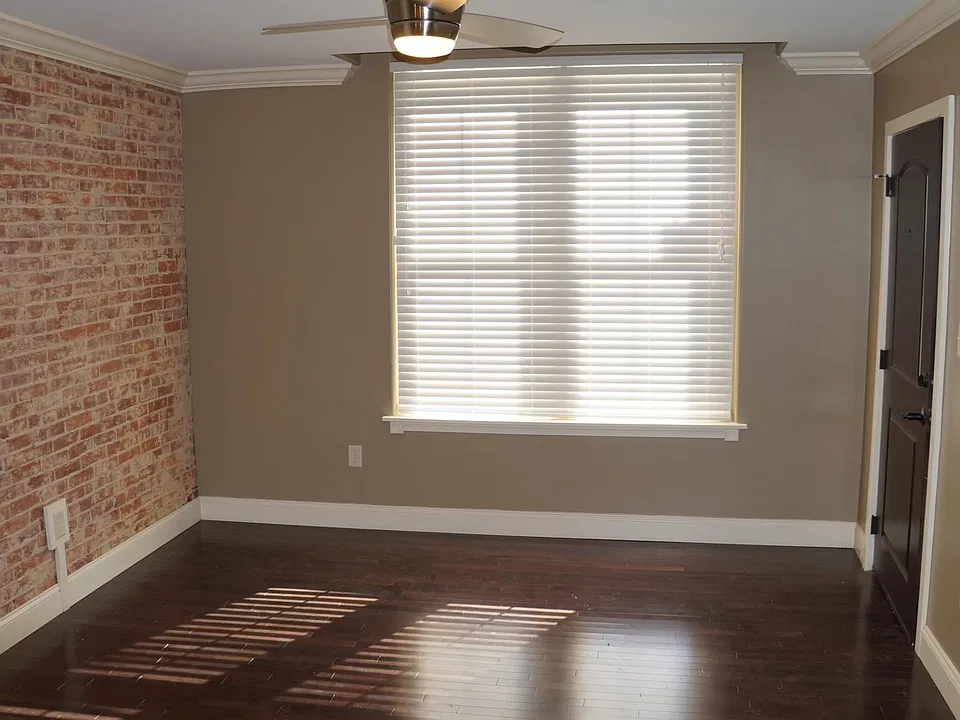 Living room with accent brick wall, the door to the right is the entrance to the apartment.