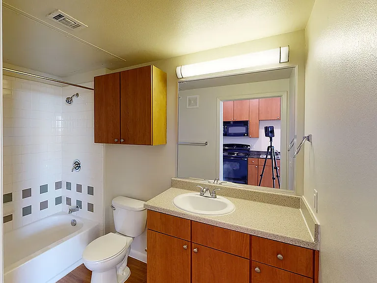 Apartment bathroom with large soaking tub and wood-style flooring.