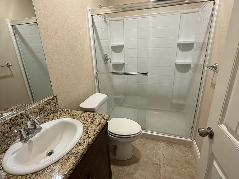 Restroom with sliding glass doors and cabinet space under the sink.