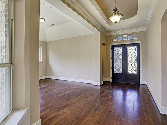 Impressive foyer with Rotunda style ceiling, dark stained front doors, gorgeous dark stained wood floors throughout , crown molding.