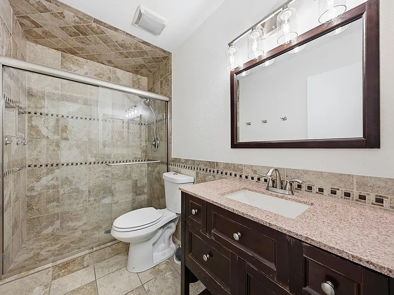 Updated bath with tiled shower, sliding glass doors, and a wide vanity with ample storage and a large framed mirror.