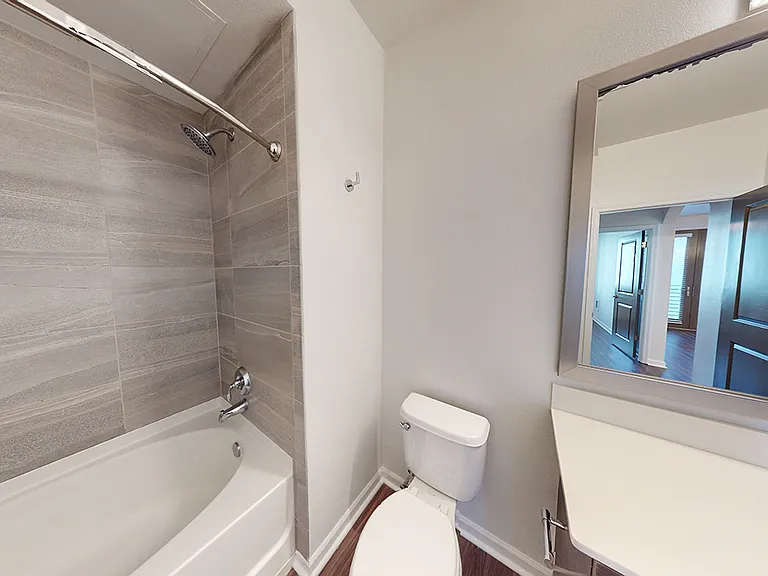 Apartment bathroom with large soaking tub and wood-style flooring.