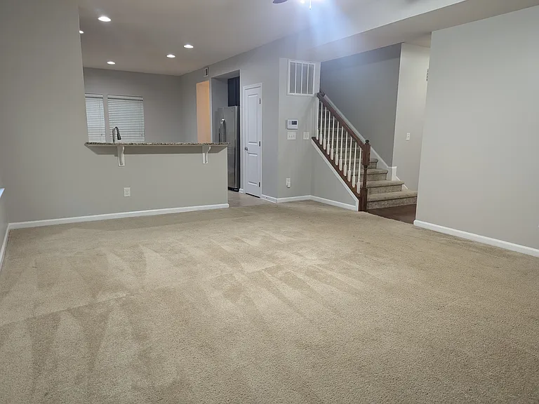 (prior to new laminate flooring) Family room looking towards kitchen/entry with stairs to upstairs bedrooms