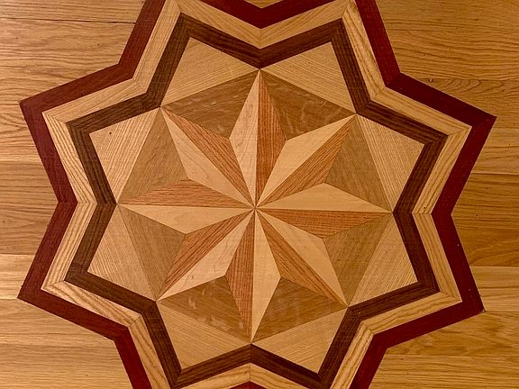 The wood floors include intricate inlays, such as this design in the entry to the unit.