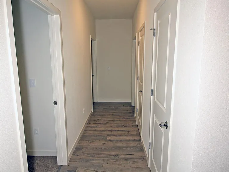 Looking down the hallway that leads to the second and third bedrooms and guest bath. Doors on the right wall open to a coat and linen closet.