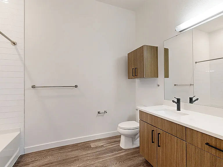 Apartment bathroom with large soaking tub and wood-style flooring.