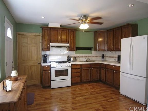 Large kitchen, beautiful flooring, ceiling fan, recessed lights. White door on left leads to backyar