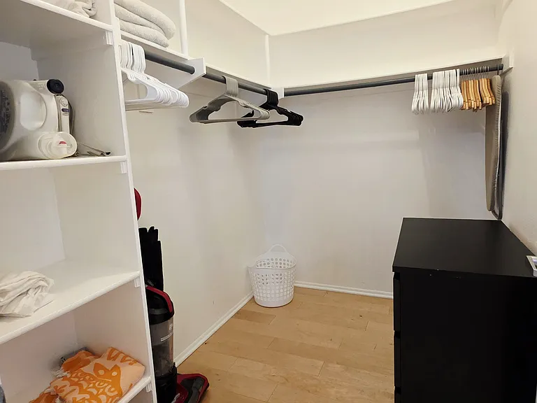 walk in closet with dresser drawers, vacuum, sheets, towels, hangers