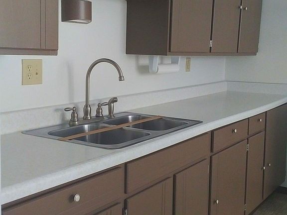 Kitchen features brushed nickel hardware and appliances are white.