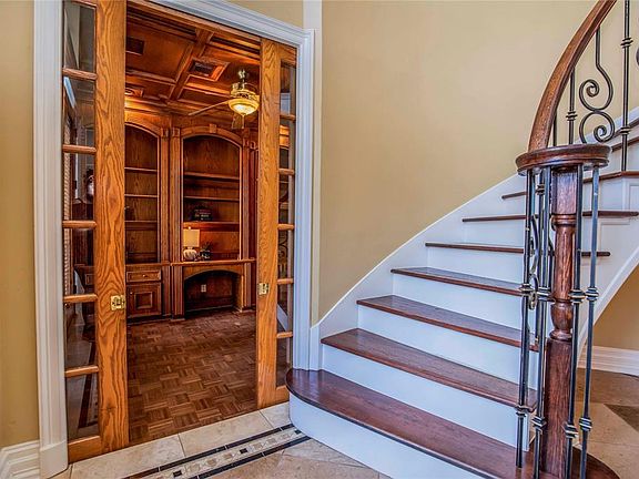 Library sits quietly at the front of the home with glass pocket doors opening to the sight of regal wood paneling & millwork, blocked ceiling and bookshelves.