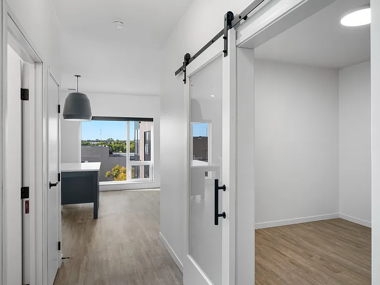 Modern apartment interior with sleek sliding barn door, elegant flooring, and an abundance of natural light from large windows. Modern apartment interior with sleek sliding barn door, elegant flooring, and an abundance of natural light from large windows.