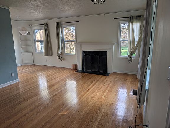 Living room and dining room with hardwood floors and a recently refurbished fireplace