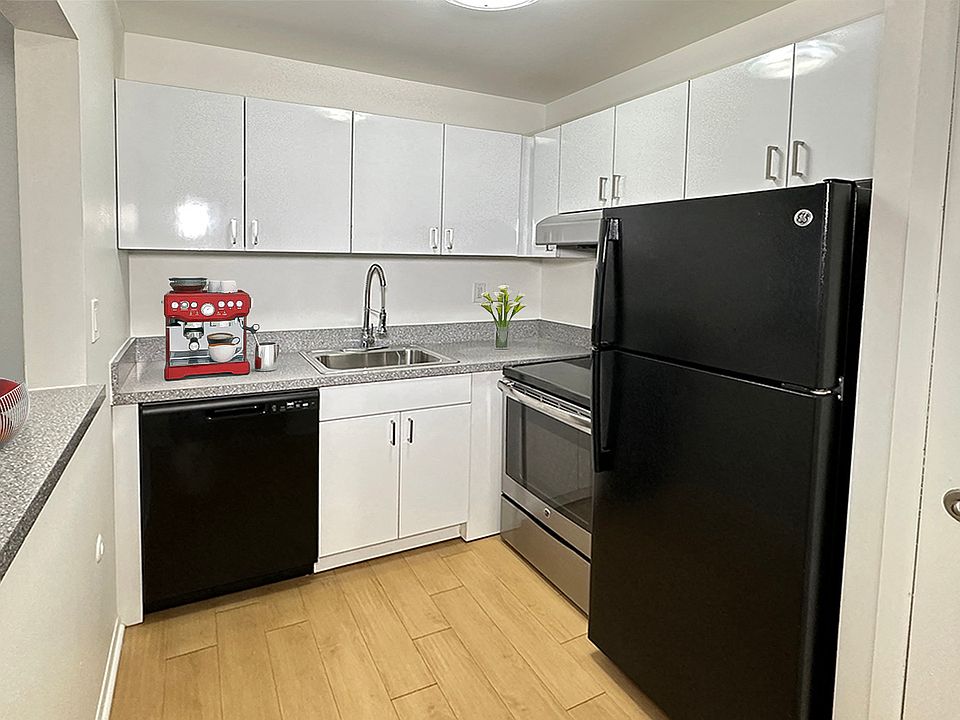 Stainless steel and black modern appliances, sleek clean white cabinetry, granite countertops, Wood plank