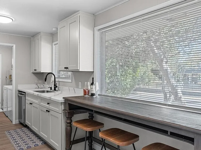Updated kitchen with ample white cabinetry, generous counter space, and a window-side bar seating area.