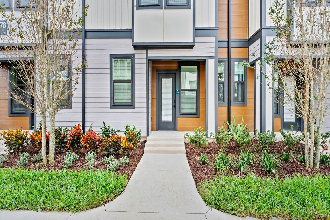 Modern townhouse exterior with sleek design, featuring large windows, landscaped garden, and inviting entrance. Ideal for stylish urban living.
