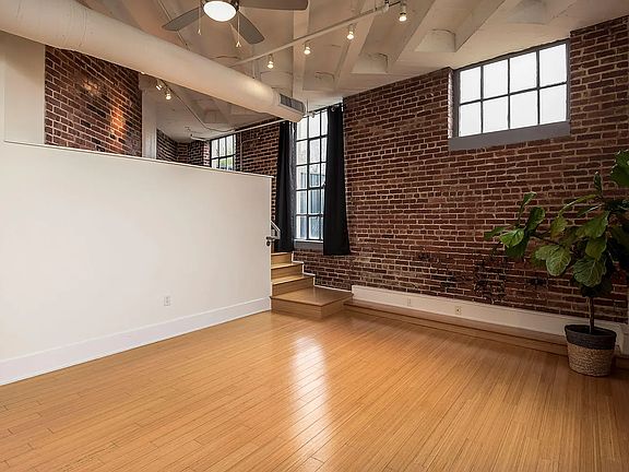 Large open living room with plenty of natural lighting, stairs lead to additional living space and patio door