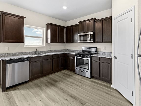 The designer kitchen features stainless appliances, granite countertops, and wood cabinetry.