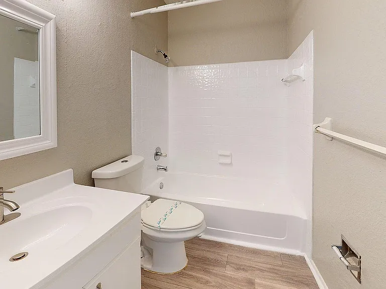Chic and modern bathroom featuring a sleek vanity, pristine bathtub, and elegant wood flooring for a luxurious touch.