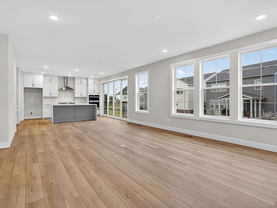 A spacious, modern kitchen with white cabinets and a gray island sits in an open-concept living area