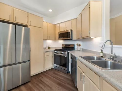 Updated Finishes kitchen with upgraded stainless steel appliances, laminate countertops, oak cabinetry, and upgraded hard surface flooring - Avalon Mission Oaks