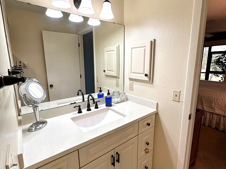 Sparkling clean and ready for you. __ We take pride in the details! The upgraded lighting in our master bath highlights the clean lines and coastal charm of the space. It's just one more reason why Unit 1003 feels like a high-end getaway.