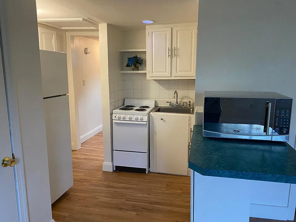 Full kitchen with electric stove, refrigerator, microwave, cabinetry, and convenient counter space.