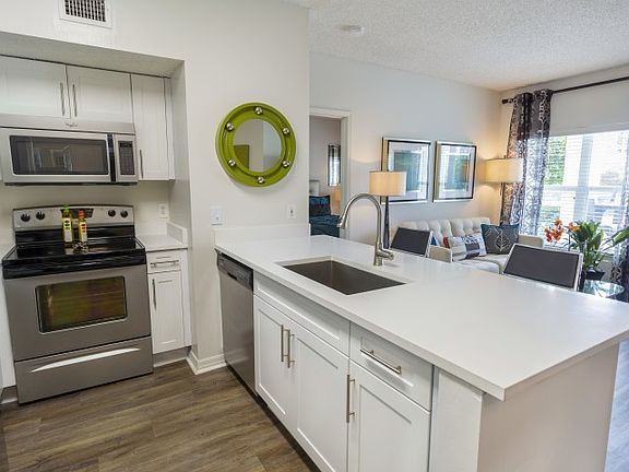 Luxury Palm Beach Gardens apartment kitchen with white wood cabinetry and wood flooring.