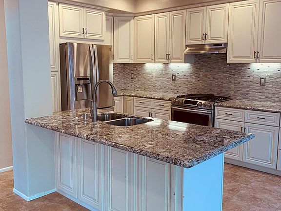 Beautiful kitchen with white cabinets, stainless steel appliances, granite counters, and room for barstools