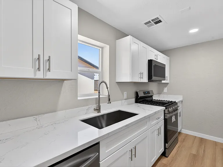 Updated kitchen with shaker cabinets, quartz-look counters, undermount sink, and stainless gas range with microwave.