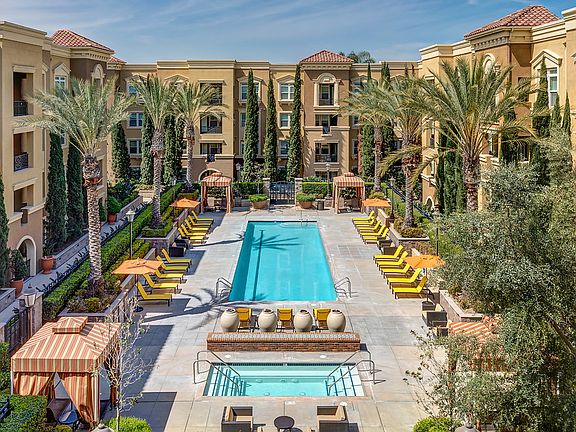 Swimming pool and spa surrounded by lounge chairs and cabanas.