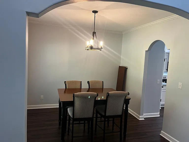 Formal dining area with arched entryways, statement lighting, and included table and chairs.