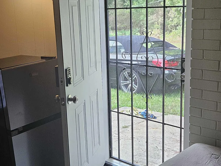Private bedroom with a bed setup, mini fridge, and direct access to an exterior entry with a security door.