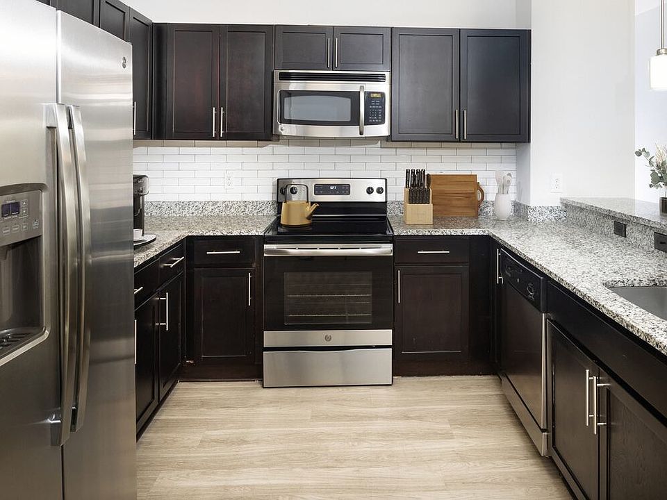 Renovated Package II Kitchen with dark cabinetry, speckled granite countertops, white tile backsplash, stainless steel appliances, pendant lighting, and hard surface flooring