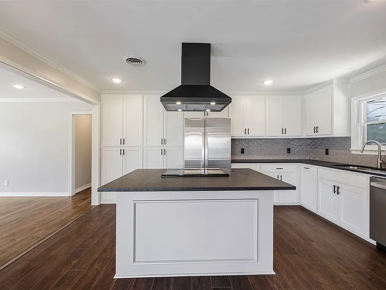 Kitchen featuring dark hardwood / wood-style flooring, stainless steel appliances, island exhaust hood, a center island, and ornamental molding