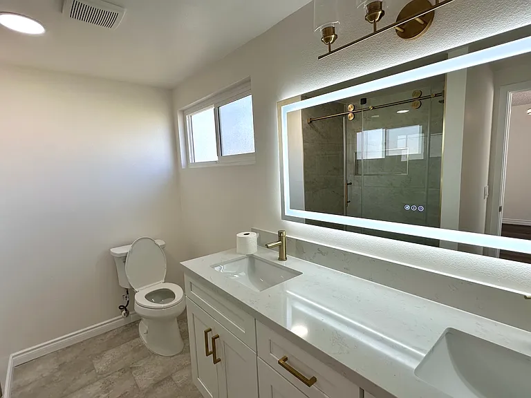Fully renovated private bathroom for the second floor master bedroom with led light mirror, double sink vanity in modern gold tones