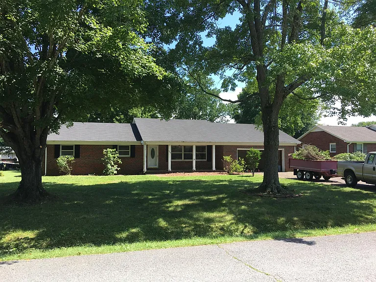 Brick home with large shade trees.