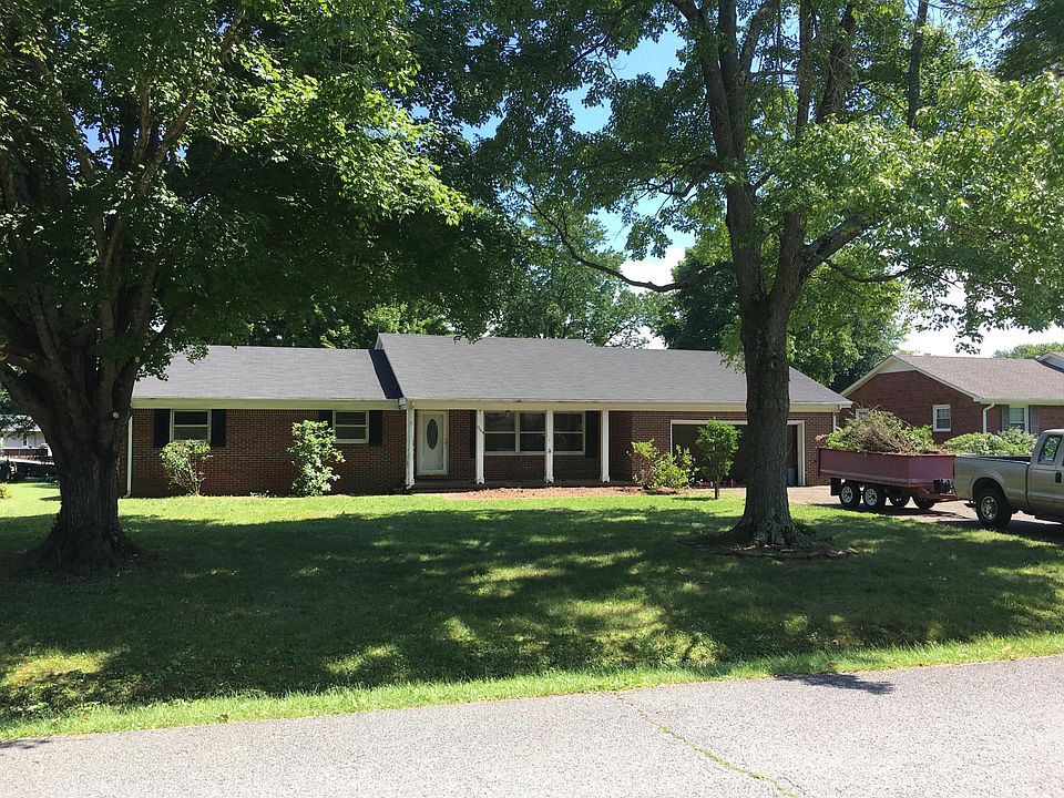 Brick home with large shade trees.