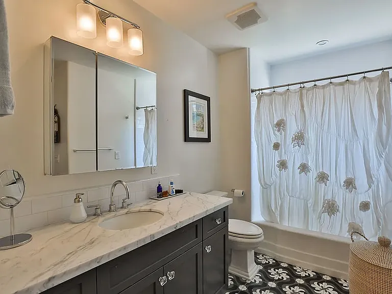 Marble counters, custom tile flooring, shower + tub, window.