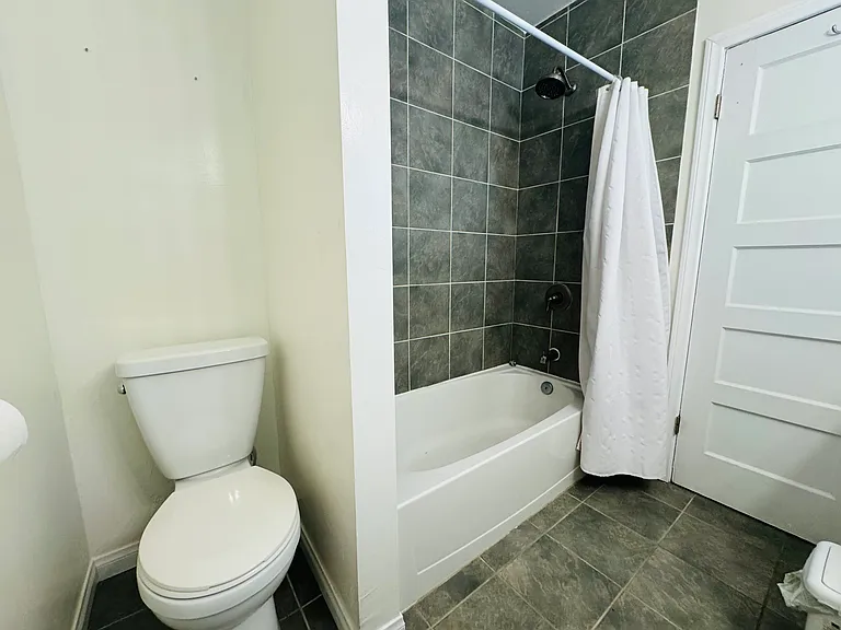 Tiled floor and shower. Privacy wall for toilet.