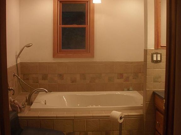Ceramic tile, wood cabinetry, and jetted tub adorn this spa-like master bath.