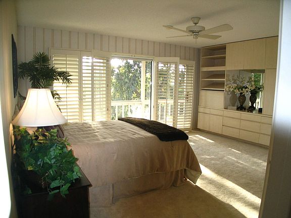Master bedroom has built-in wall unit and a wall of doors to balcony