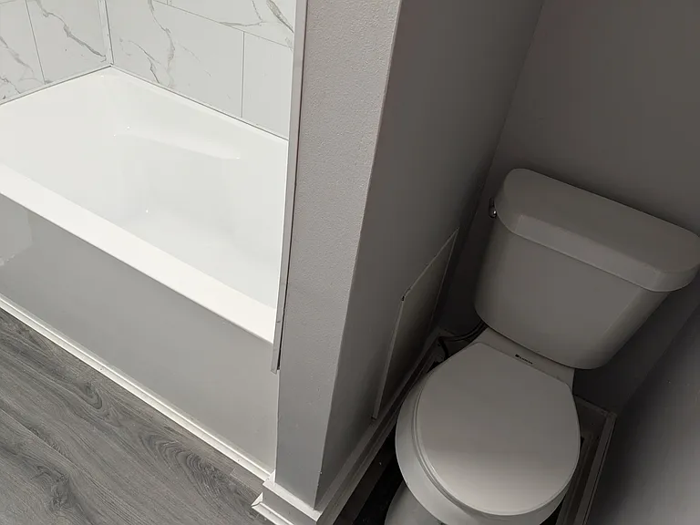 Recently installed toilet, tub and surround with luxury vinyl floor