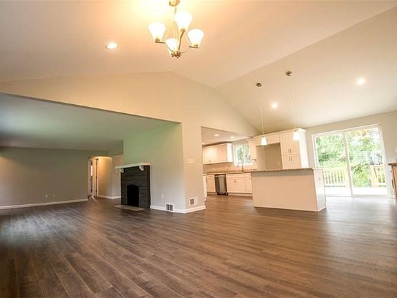 View from dining area opening up to the living room and kitchen with large island with seating for three.  Sliding glass door op