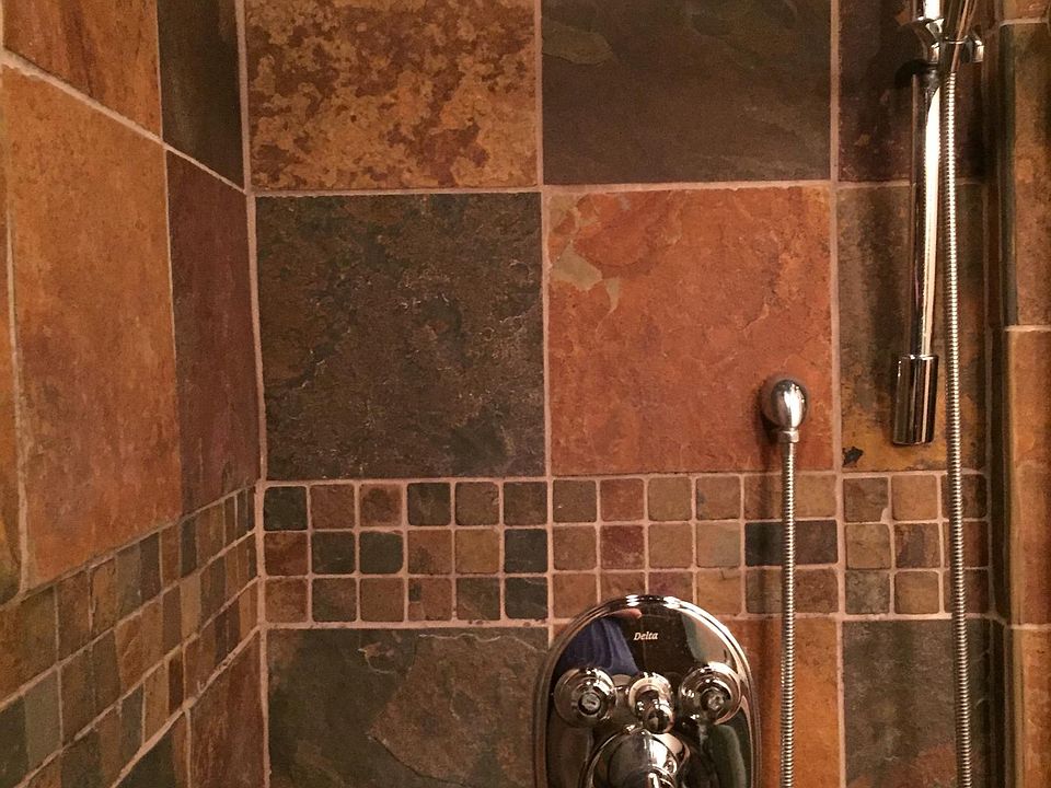 The large walk-in shower features natural slate tile, built in bench, and sliding glass doors.