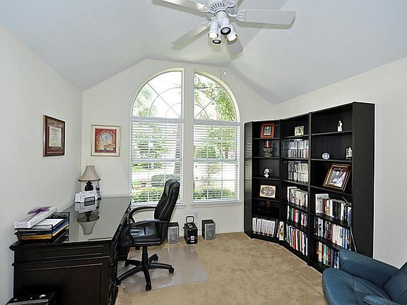 Study with vaulted ceiling and arched window that overlooks the front yard