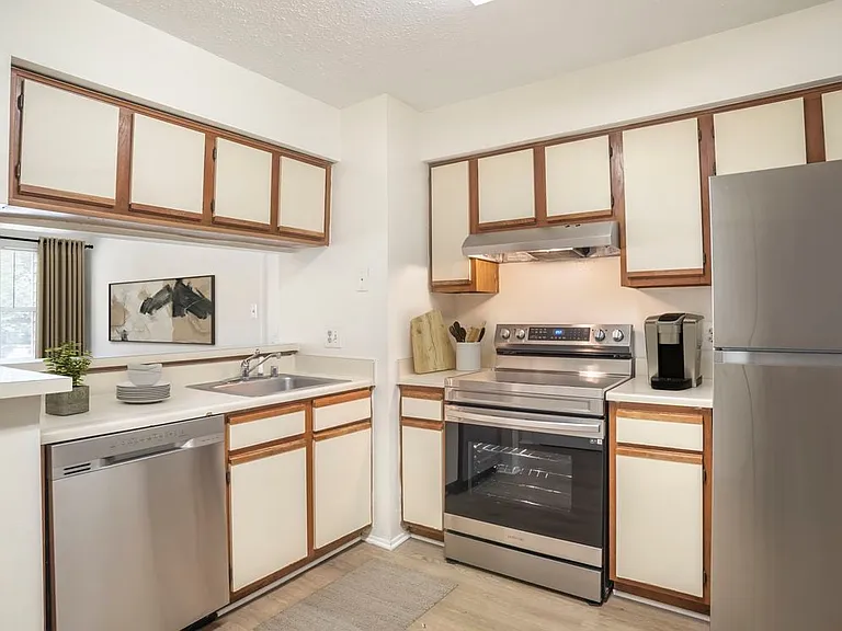 Renovated Meadows I kitchen with stainless steel appliances, cream cabinetry with wood trim, beige laminate countertops, and hard surface flooring