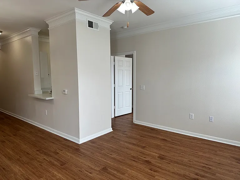 Bright and spacious living area featuring elegant wood-style flooring and a ceiling fan with natural light flowing in. Bright and spacious living area featuring elegant wood-style flooring and a ceiling fan with natural light flowing in.