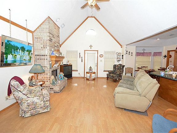 BIG VAULTED LIVING ROOM WITH LAMINATE WOOD FLOORS, CROWN MOLDING AND WOOD BURNING FIREPLACE. DOOR LE