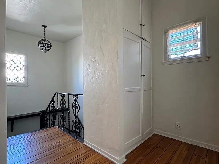 Upstairs landing - built-in closet, decorative window, hardwood floors.